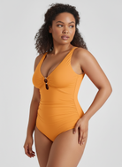 Woman wearing a mustard yellow swimsuit on a plain background